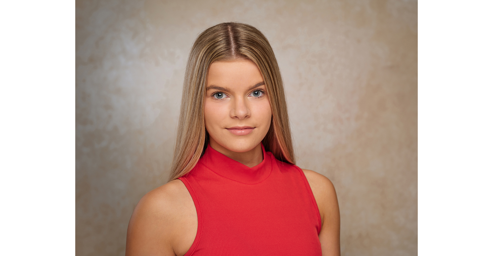 young blonde hair dancer in red top front of cream canvas backdrop